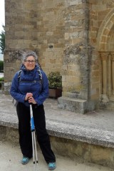 woman standing with hiking gear in front of an old buildling